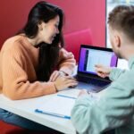 a man and a woman sitting at a table with a laptop