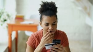 Woman looking at phone with credit card in hand